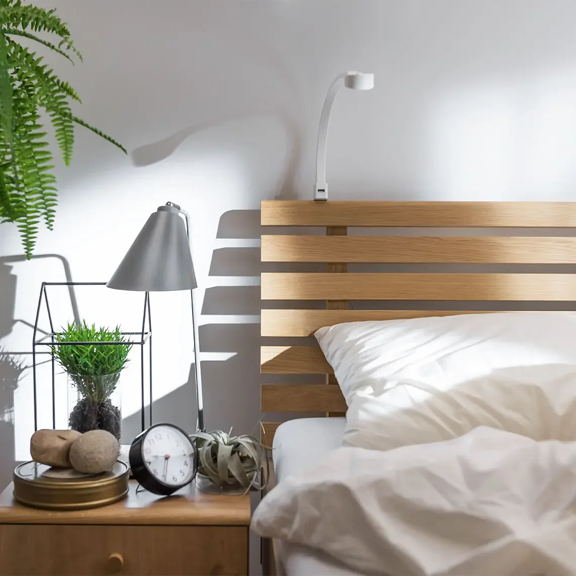 Minimalistyczna lampka nocna na drewnianym stoliku przy łóżku